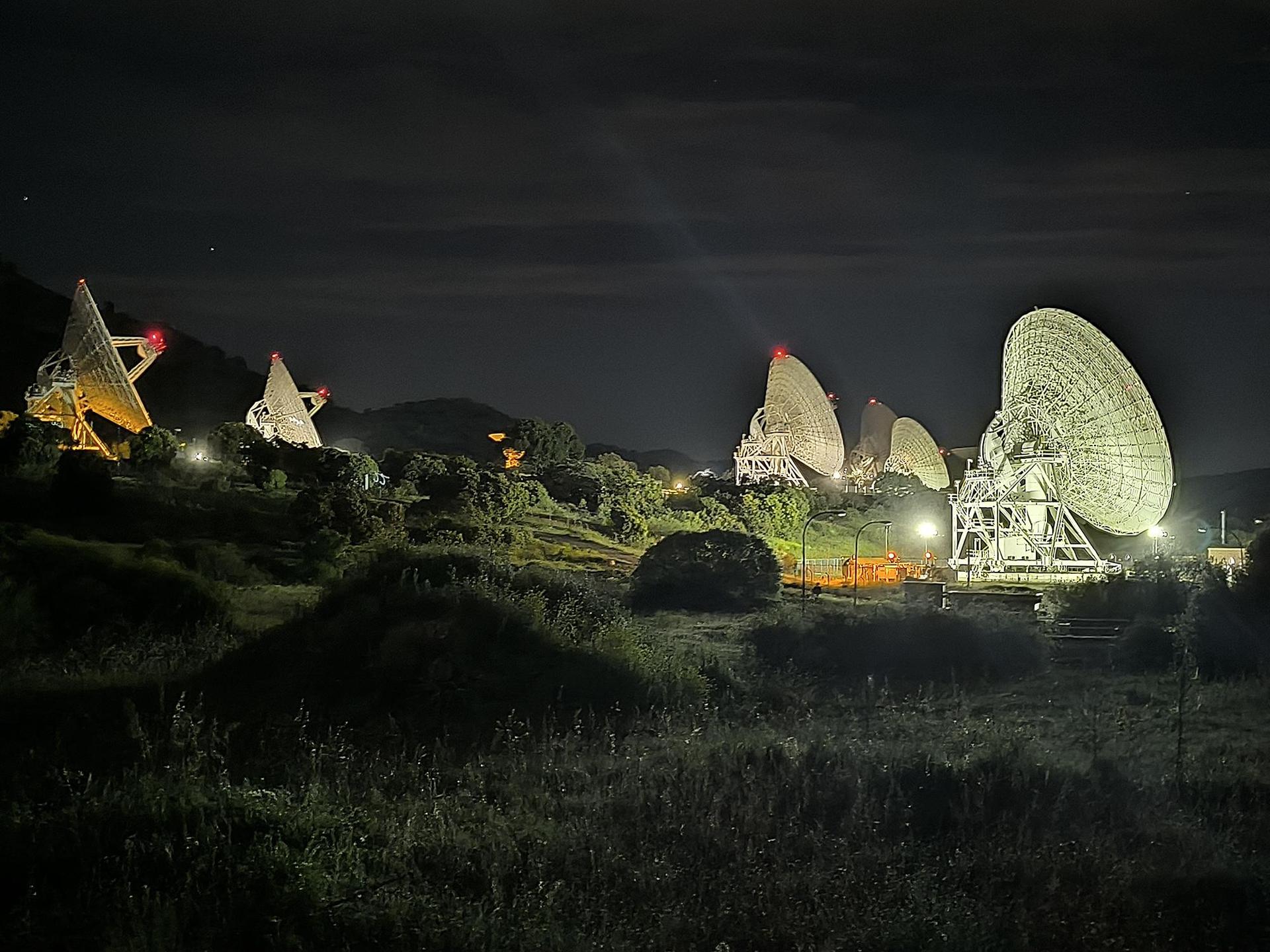 Multiple large radio dish antennas of NASA's Deep Space Network arrayed together against the sky