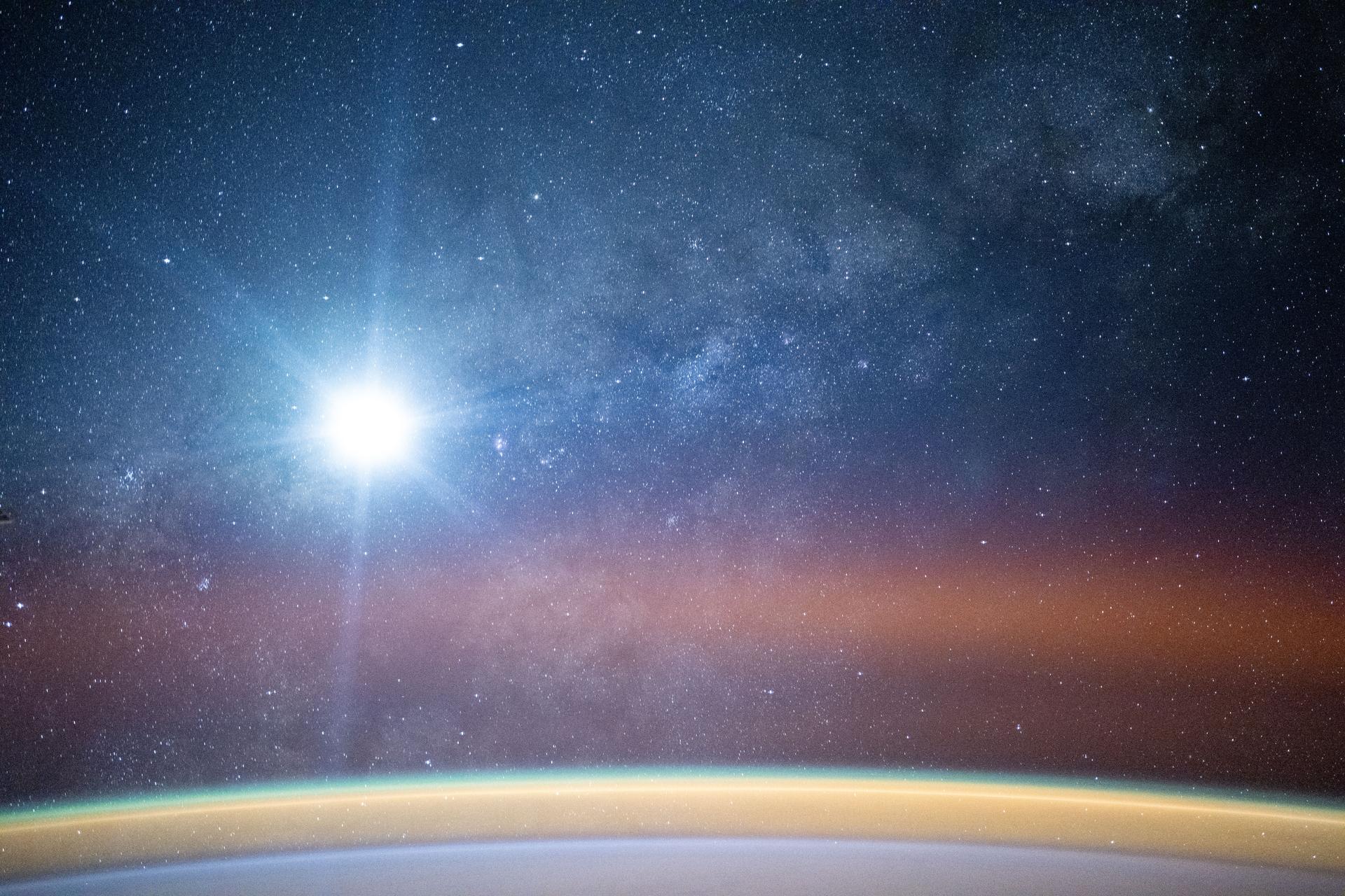 A bright airglow blankets Earth's horizon as the Milky Way illuminates the night sky